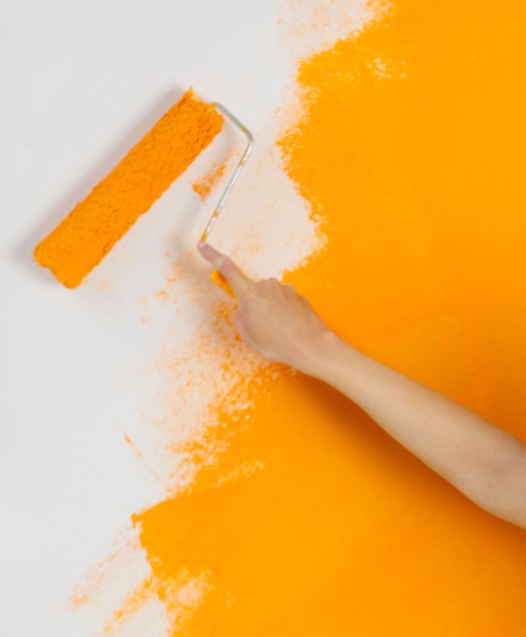 Weiße Wand wird orange gestrichen mit Farbrolle