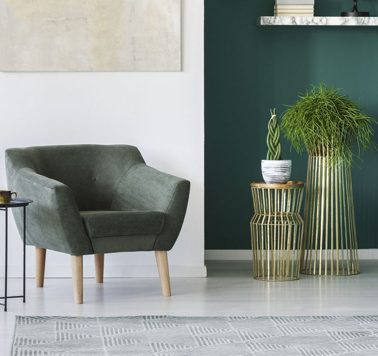 Weiße und grüne Wand mit ghrünem Sessel und Pflanzen davor