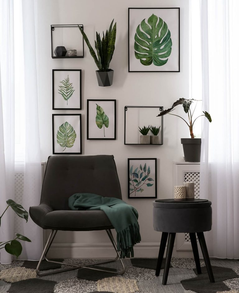 Sessel vor Wand mit Bilderrahmen mit Blättermotiven