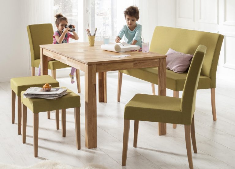 Holzesstisch mit grünen Stühlen und Kindern