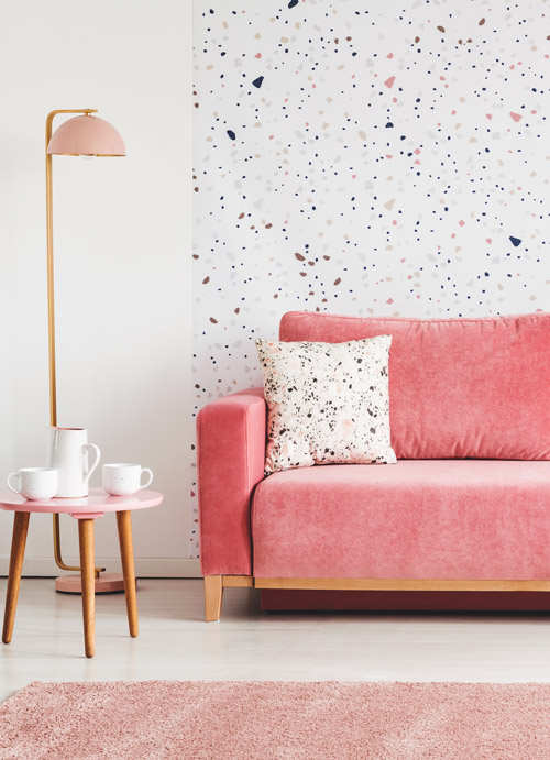 Sofa in dunklem rosa vor Wand mit Punktmuster