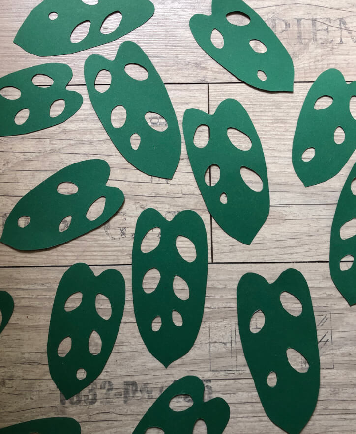 Ausgeschnittene Blattformen aus grüner Bastelpappe mit ausgeschnittenen Blatt-Löchern
