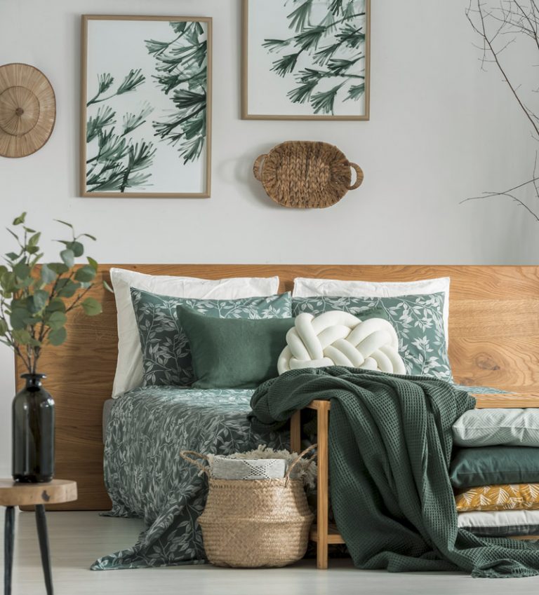 Bett vor Holzwand, Bilder und Bettwäsche mit Pflanzenmotiv