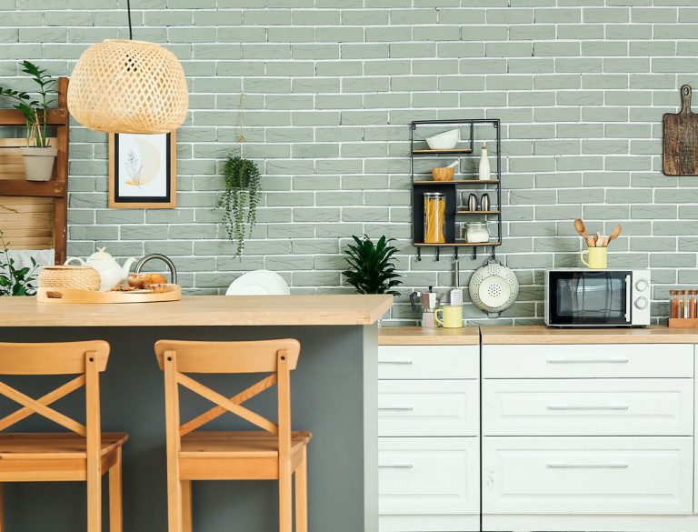 Modernen Küche mit weißen Fronten, heller Arbeitsplatte aus Holz und salbeifarbener Rückwand in Backsteinoptik!