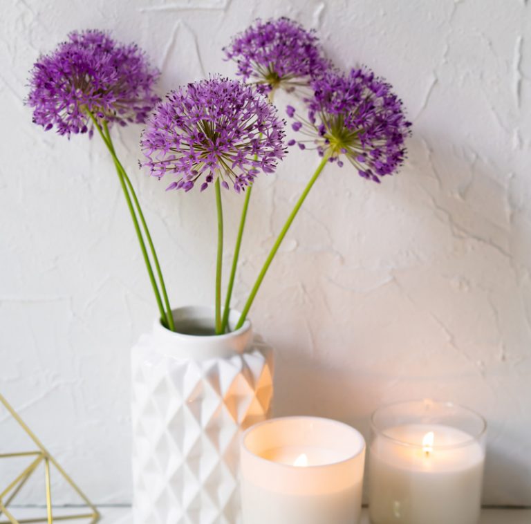 Lila Zierlauch in weißer Vase mit Kerzen
